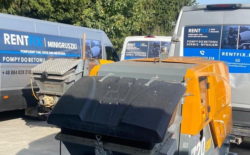 Pomarańczowa pompa do betonu z czarną pokrywą leja, za nią busy z oklejeniem RENTFIX.